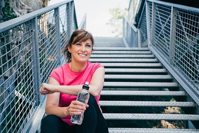 Active Woman Drinking Water on Stairs After a Run